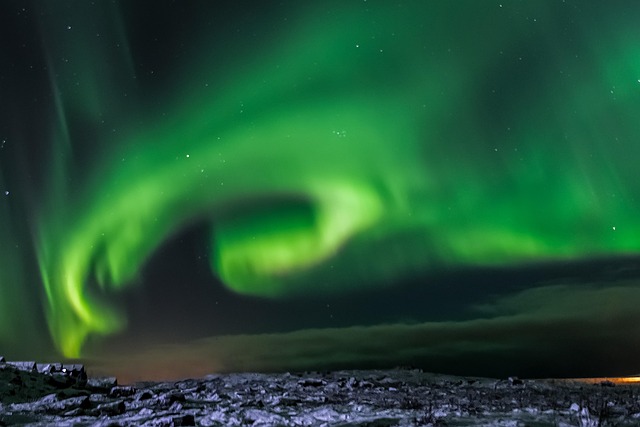 Aurora Borealis over a snowy Icelandic landscape with mountains