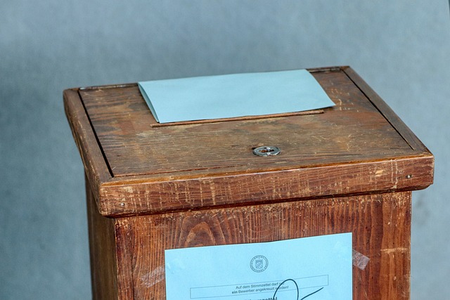 A person inserting an early voting ballot into a secure drop box